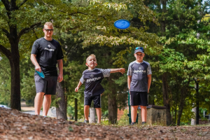 Disc Golf Gifts for Dads: Photo of father playing disc golf with sons. 