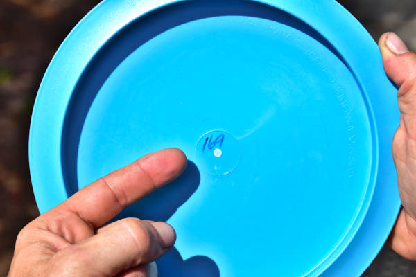 Finger pointing to written weight of disc. Disc weight is an important factor in disc selection.