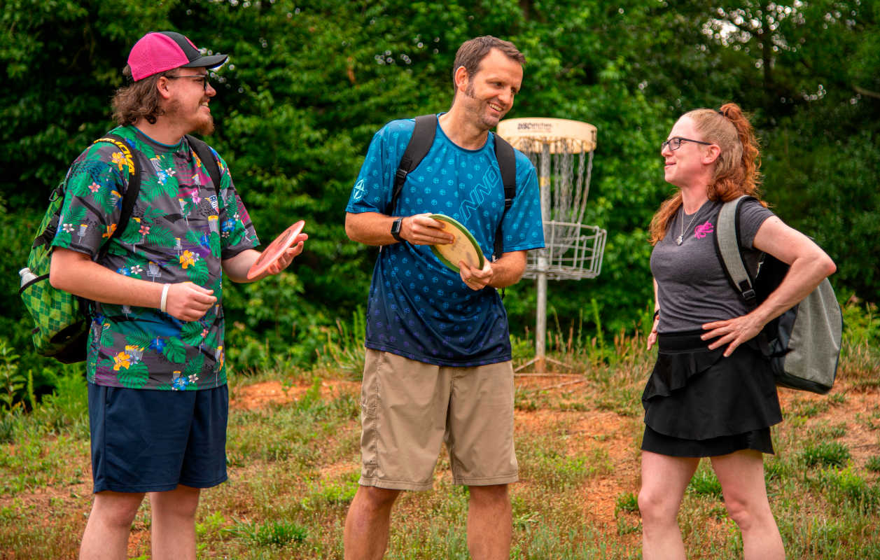 Group of friends having conversation about disc golf while showing off INNOVA apparel 